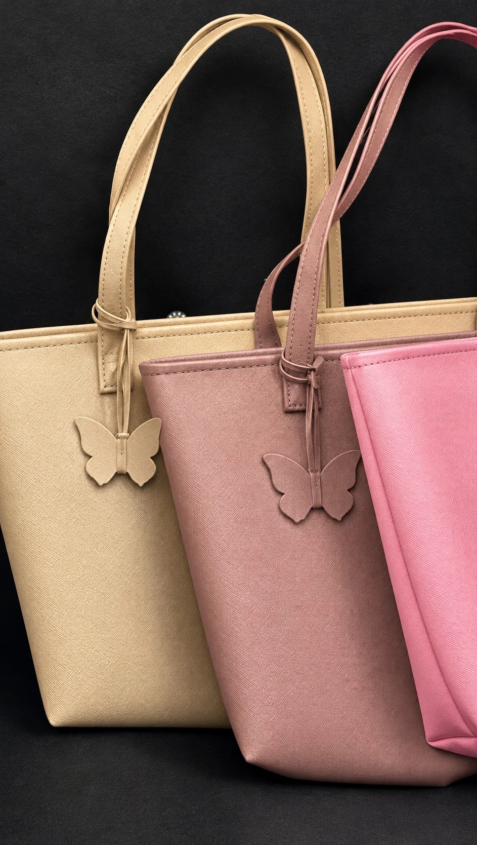 Leather butterfly charms hanging from the straps of sand, mauve and pink MAEV totes